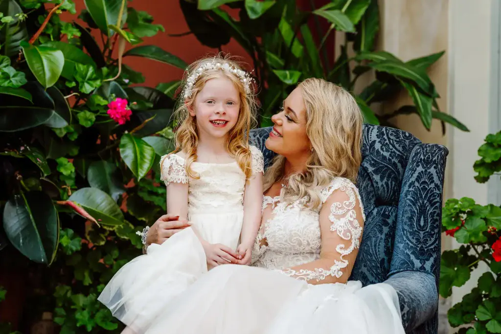 flower girl sits on brides lap in conservatory