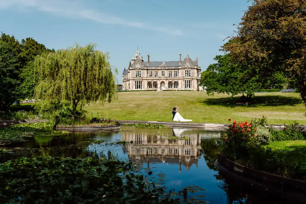 bride and groom kiss in front of the lake at clevedon hall in somerset
