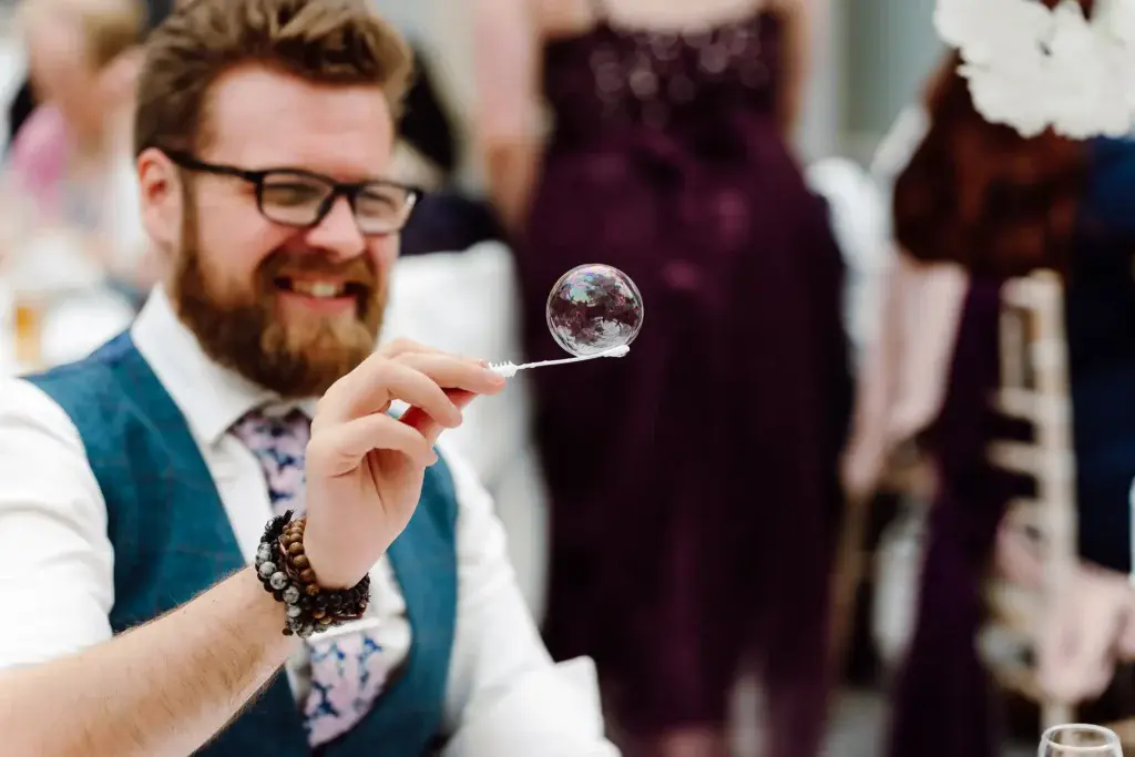 man balances bubble on the end of a bubble wand