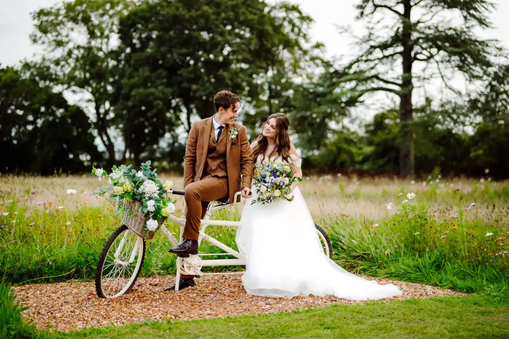 bride and groom sitting on a bicycle in the gardens of St Tewdrics House in Wales
