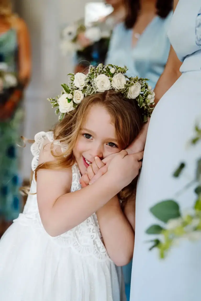 little flower girl cuddles her mums hand as she is candidly captured by her wiltshre wedding videographer