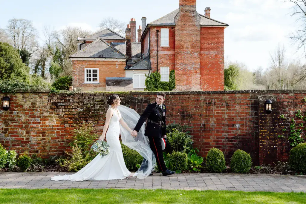 a groom in military uniform and bride holding hands while walking in a wiltshire wedding videographer photo