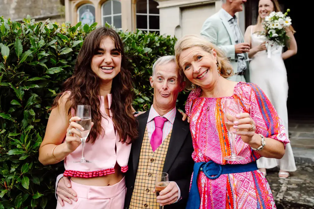 wedding guests posing with big smiles for wedding photographer and videographer