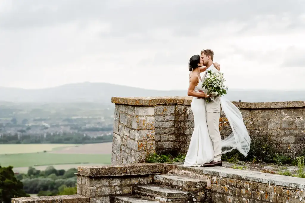 bride and groom kiss at with the view of the cotswolds landscape behind them on their wedding day