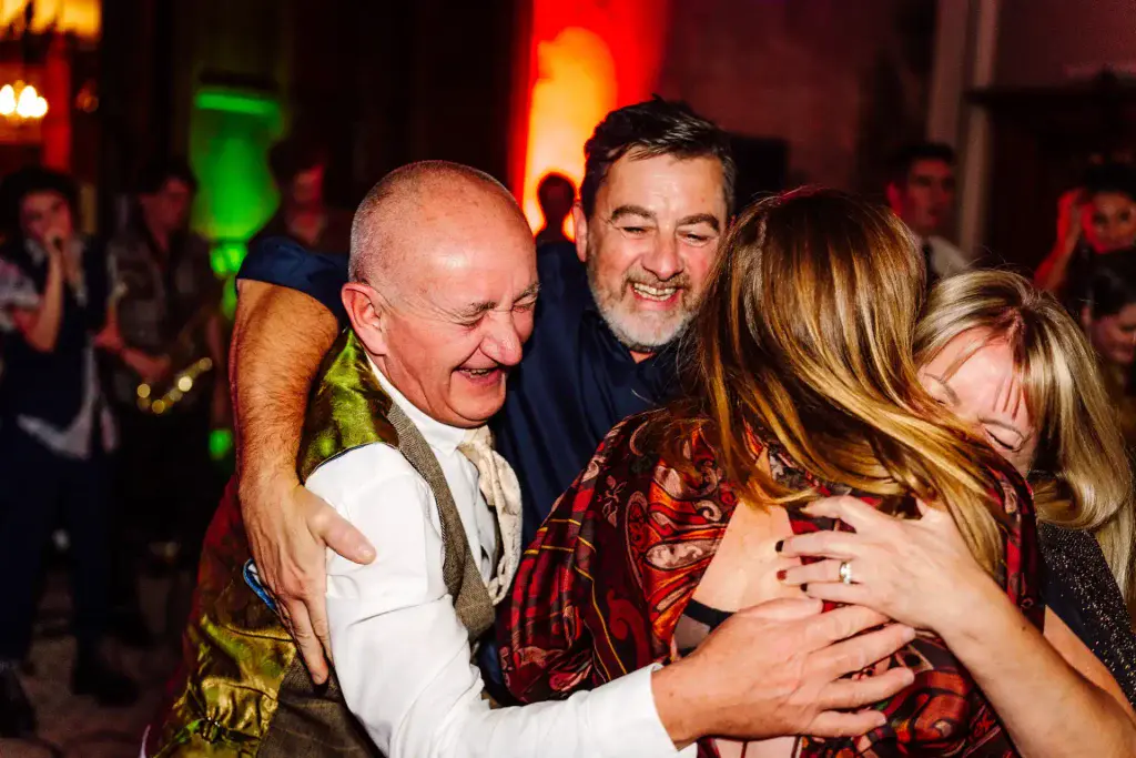 guests at a wedding hug and laugh one another on the dance floor