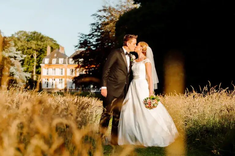a man and woman kissing in front of a building as they pose for their destination wedding photographer