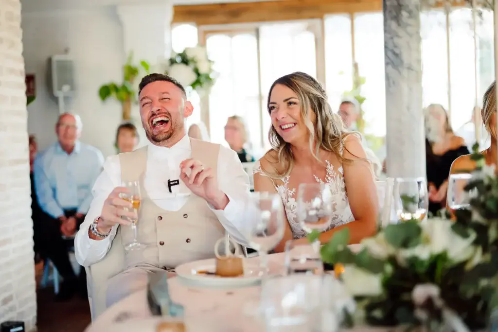 bride and groom laugh out loud while sat down listening to speeches at a wedding in finca monasterio in spain