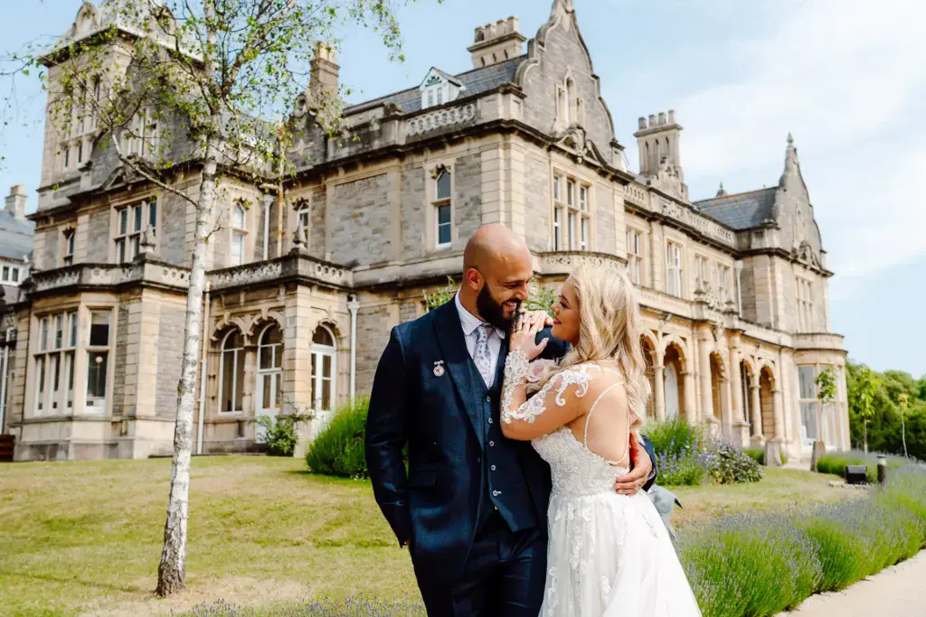 bride and groom are captured by white villa wedding videographer and photographer as they lean into one another and share a loving glance on a summers day at Clevedon Hall wedding venue in Somerset