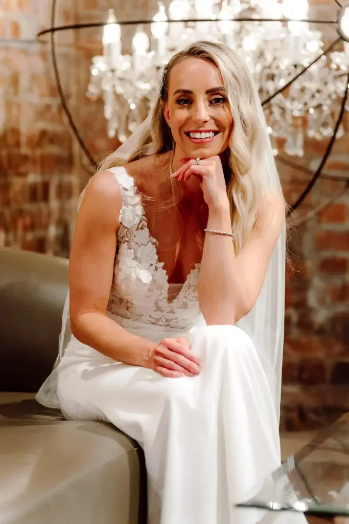 bride looks relaxed and smiling while she rests her chin on the back of her hand while sat down at the avon gorge hotel in bristol