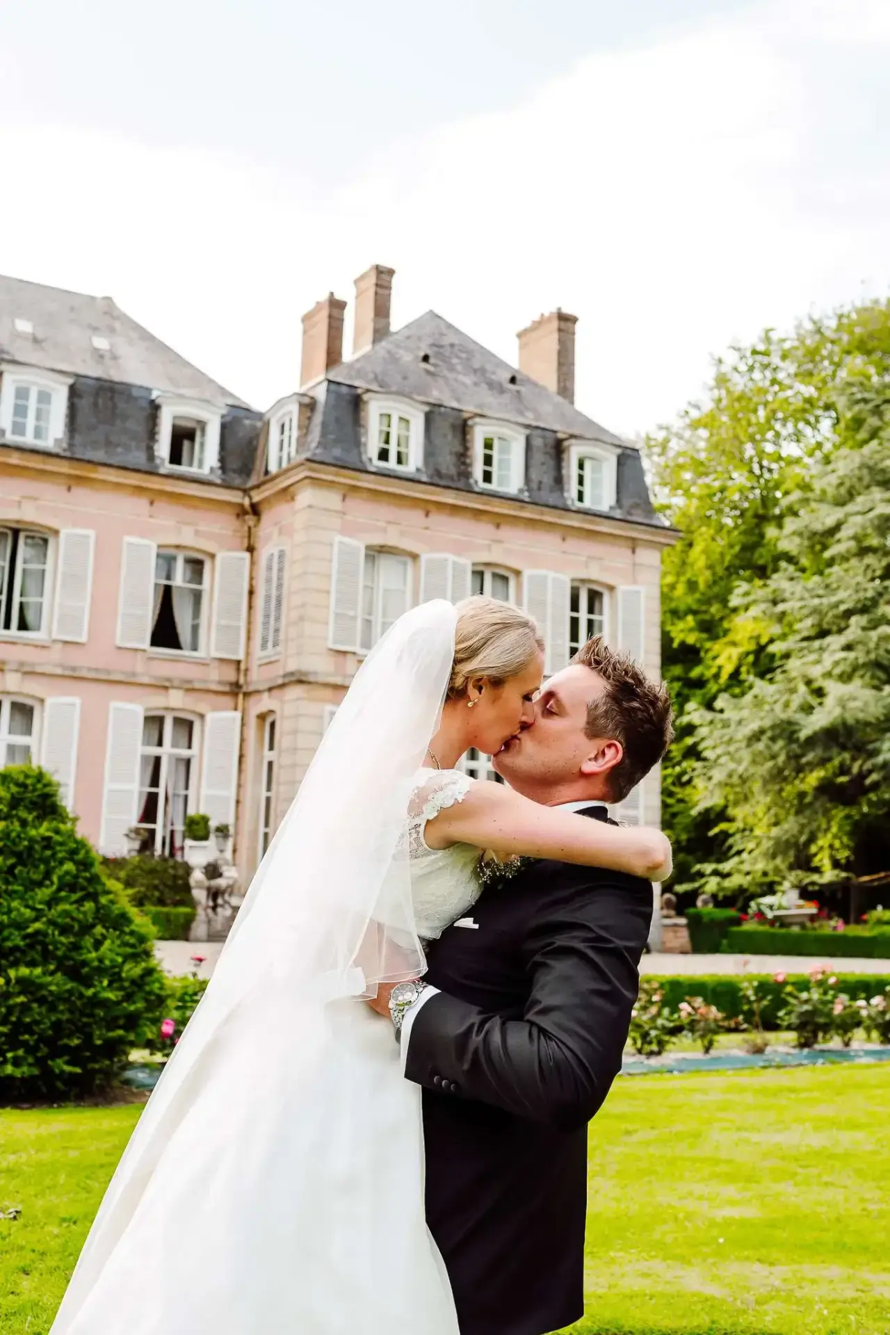 a man and woman kissing in front of a wedding venue in france