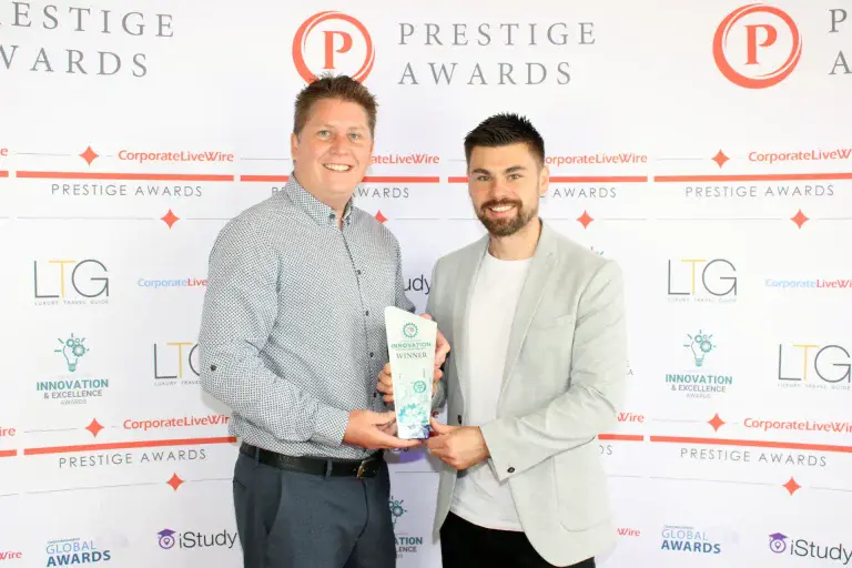 phil and sam from white villa hold the prestige awards trophy and pose for the camera as they accept this award for wedding videography company of the year