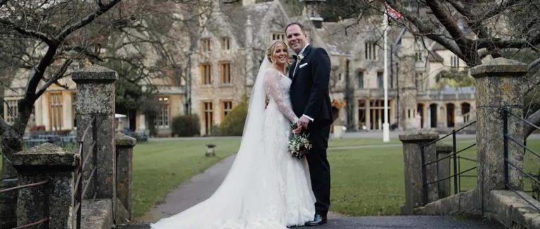 bride and groom pose outside wiltshre wedding venue castle coombe