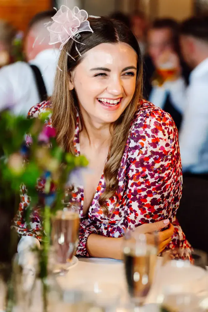 a woman smiling at the camera while sat at a wedding table at the avon gorge hotel
